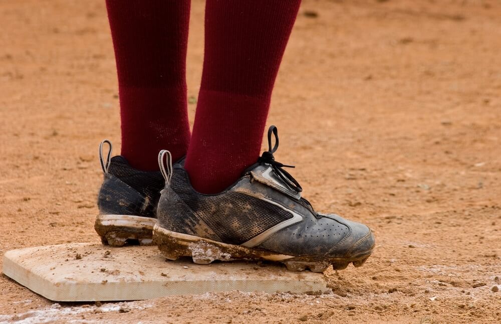 Player stands on base in youth baseball cleats